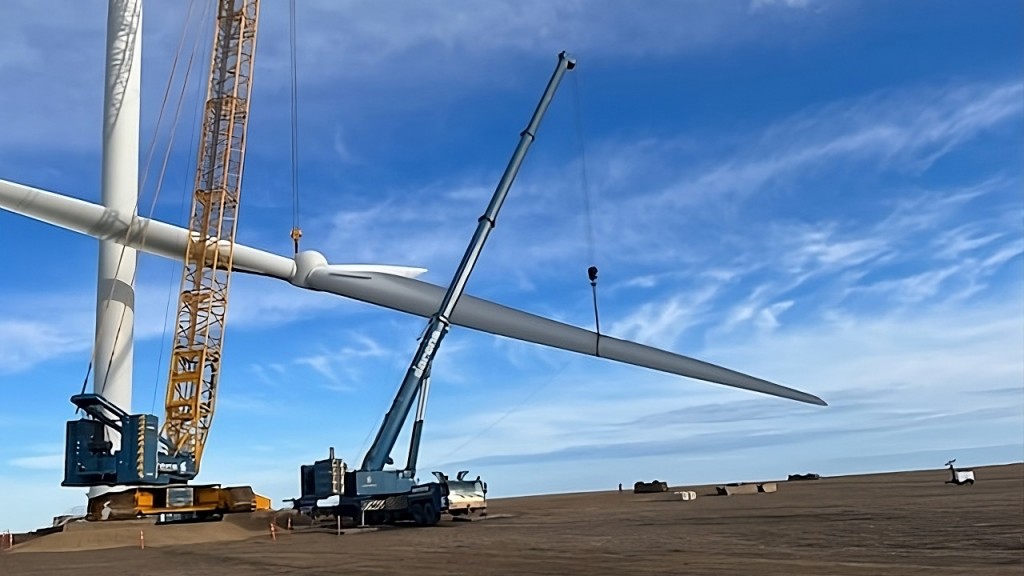 Two cranes work together to lift a wind turbine blade.