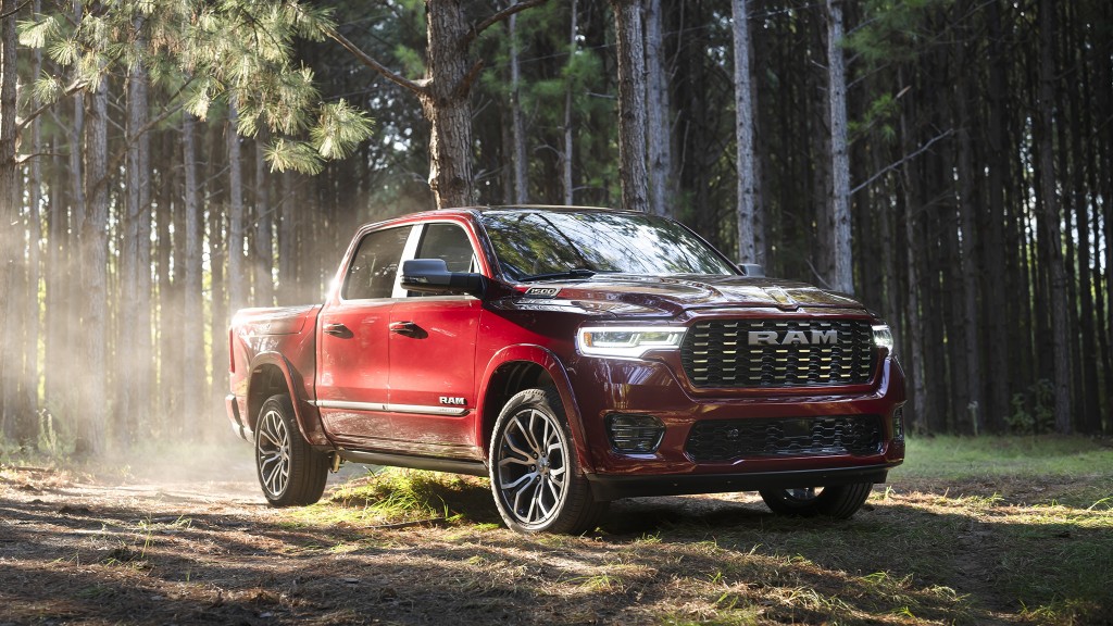 A red pickup driving through a wooded area.