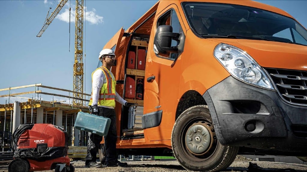 A worker moves tools into a service van