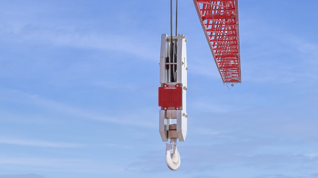 A hook block hanging from a tower crane in front of a blue sky.