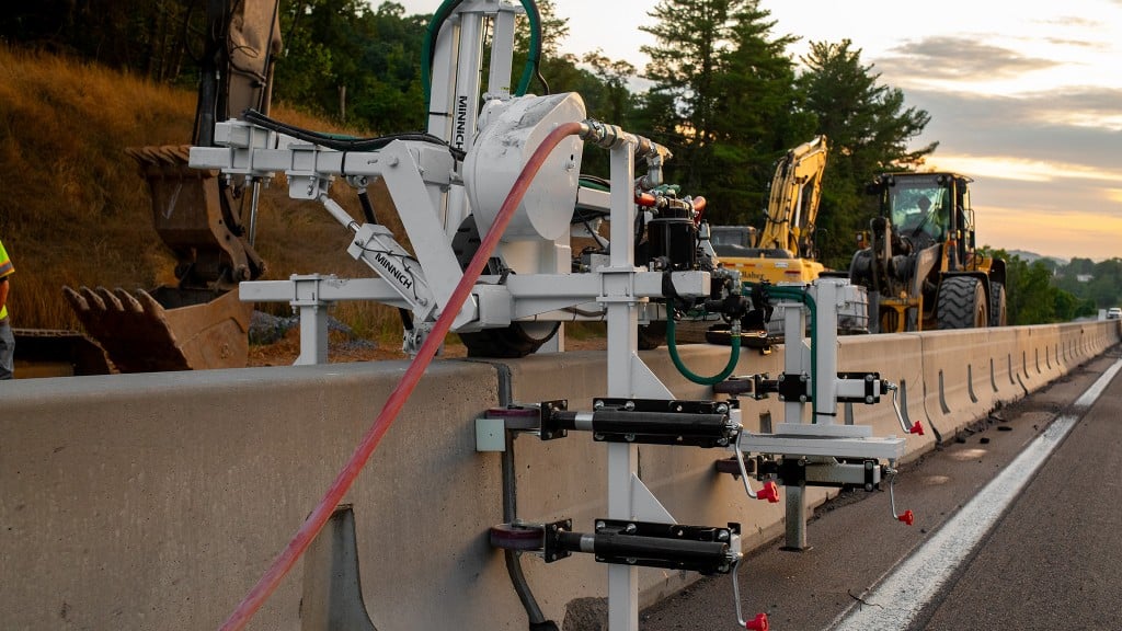 A barrier wall drill set atop a barrier wall along a roadside.