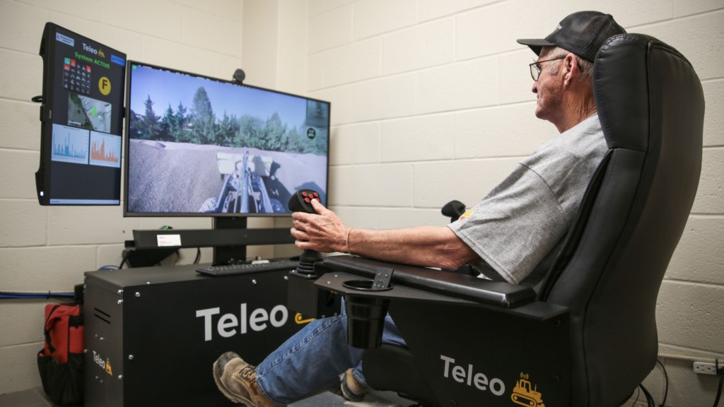 An operator sits in a remote operating station with monitors and controls.