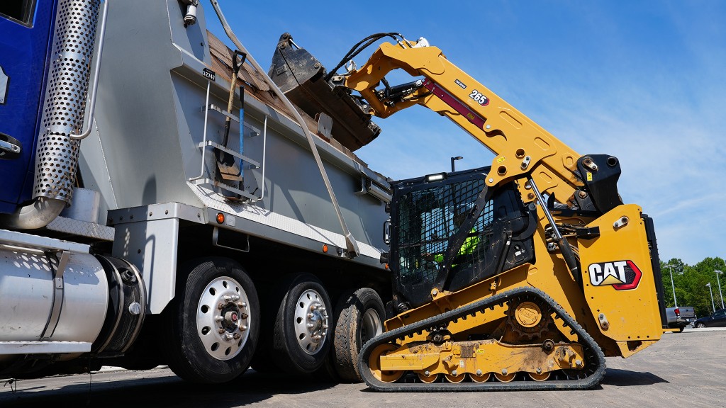 A compact track loader loading a dump truck.
