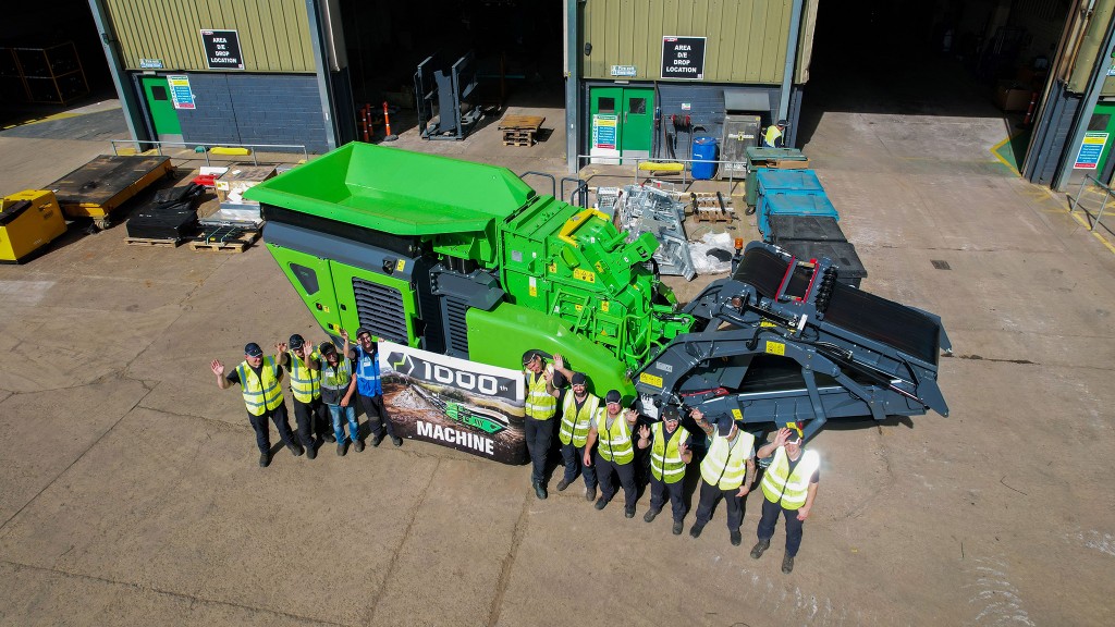 A group of workers standing in front of an impact crusher outside a factory.