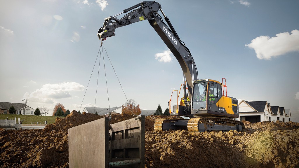 An excavator lifting a concrete structure from a trench