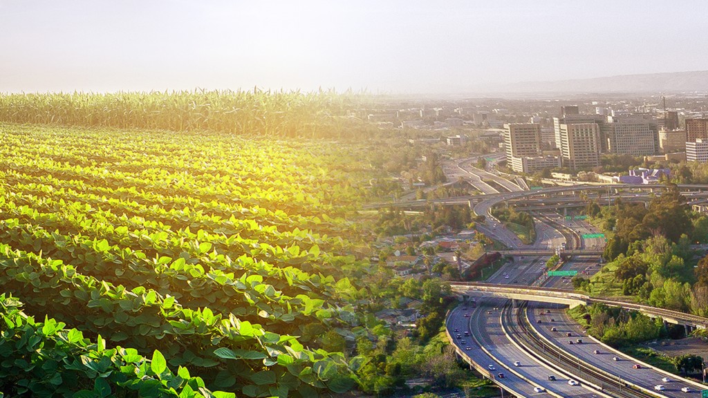 An image depicting a green farm field and a city.