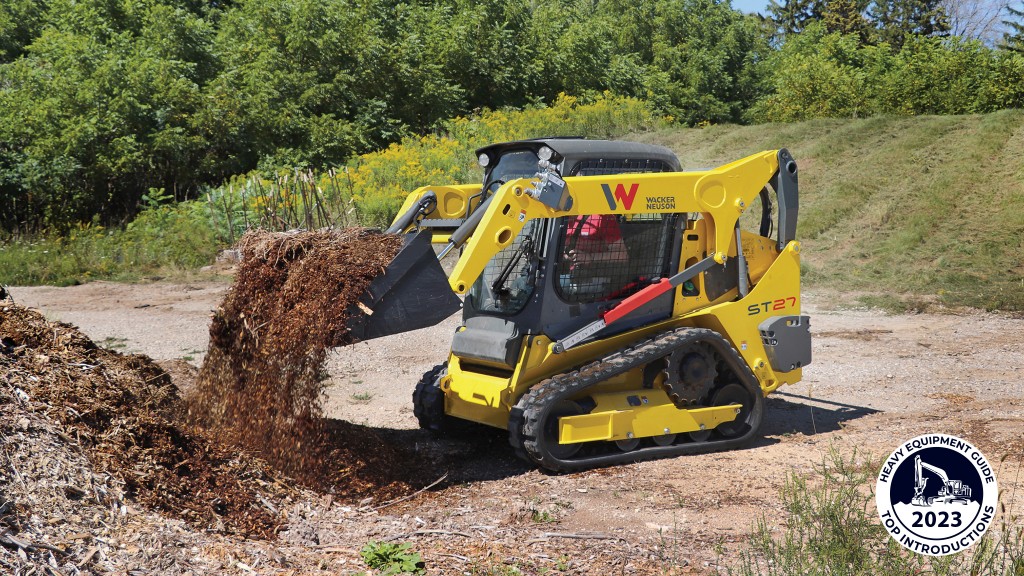 A compact track loader dumps out a bucket of mulch
