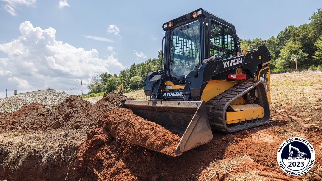 A compact track loader moves dirt with its bucket