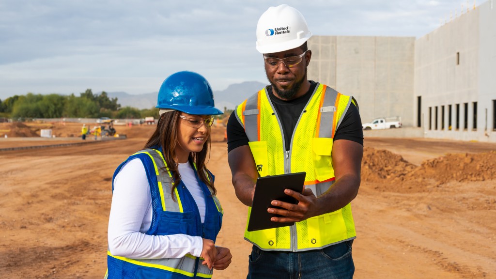 Two people look at a tablet on a job site