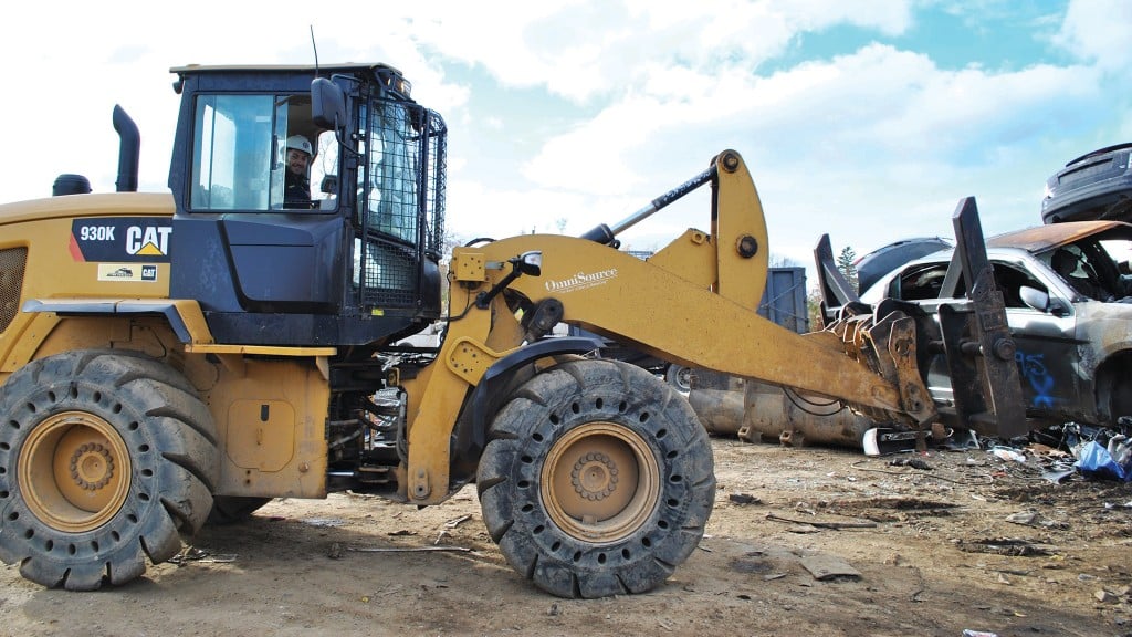 A wheel loader equipped with forks moves a car