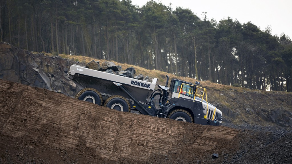 An articulated hauler driving down a steep slope in a quarry.