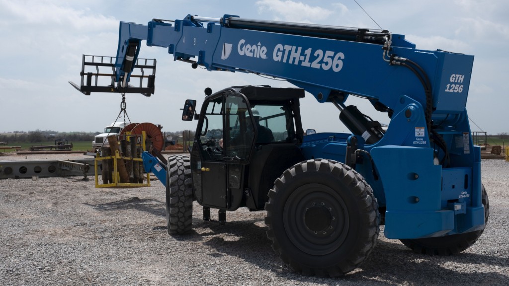 A telehandler transports a crate of materials that hang off its forks