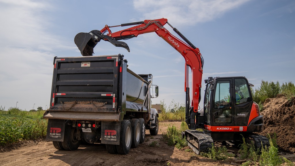 A compact excavator loading a dump truck.
