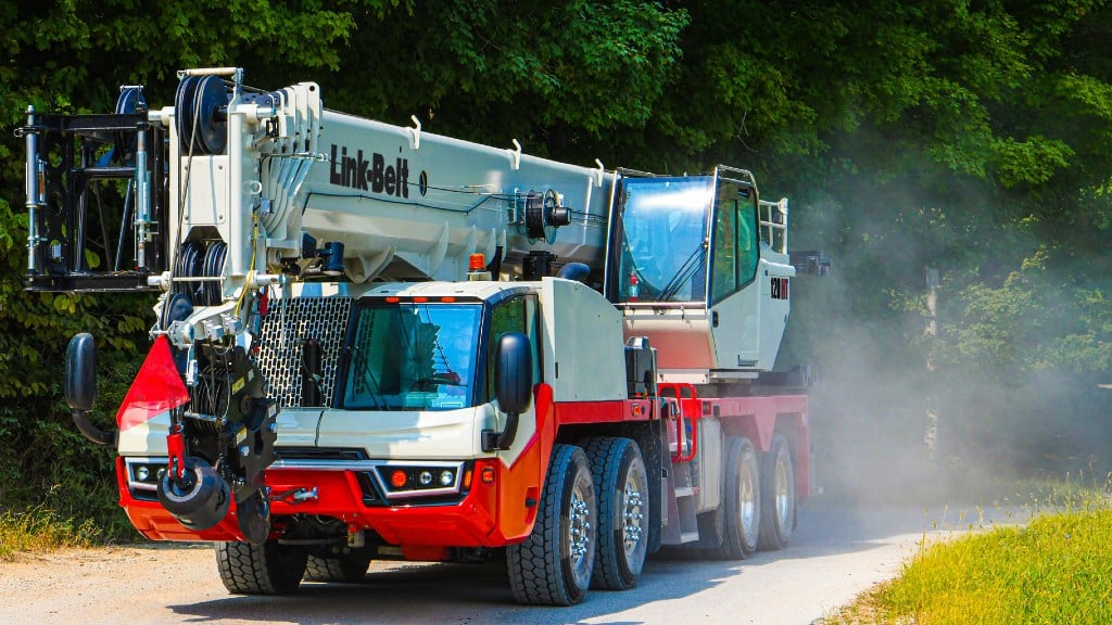 A hydraulic truck crane drives down a dirt road