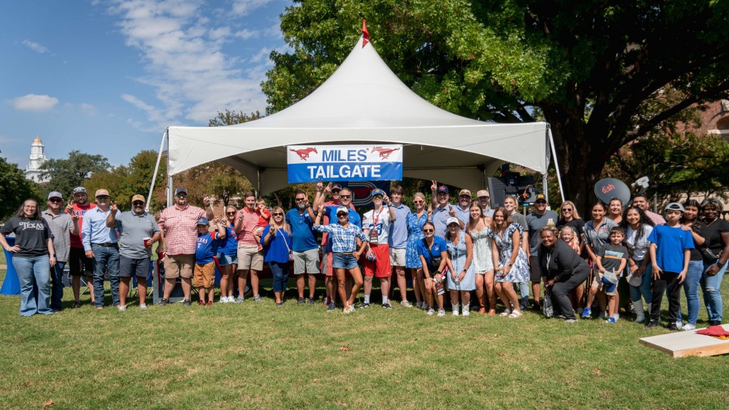 A group of people pose for a photo at a tailgate party