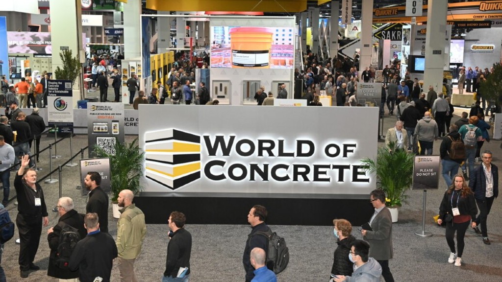 People walk around a World of Concrete sign
