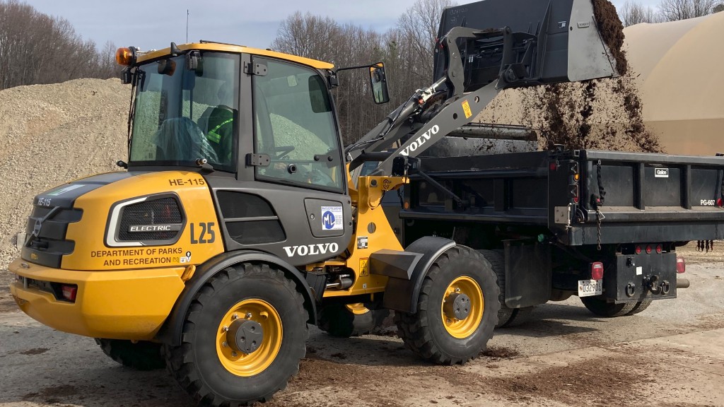 A compact wheel loader dumps soil into the back of a truck