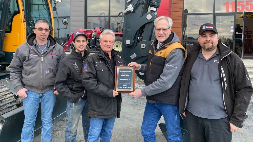 A group of people accept a dealership plaque