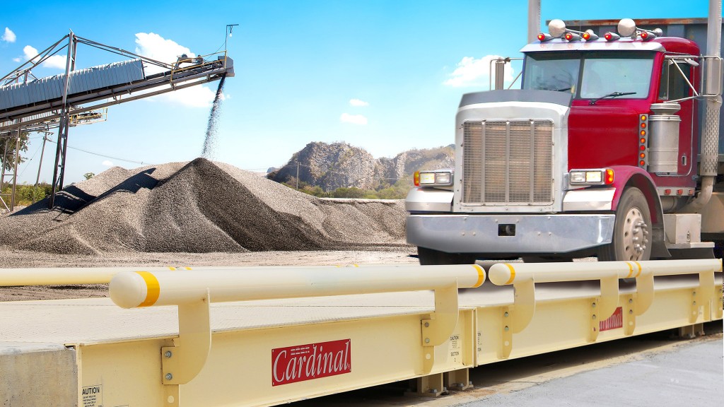 An illustration showing a truck scale in the foreground with an aggregate conveyor and stockpile in the background.