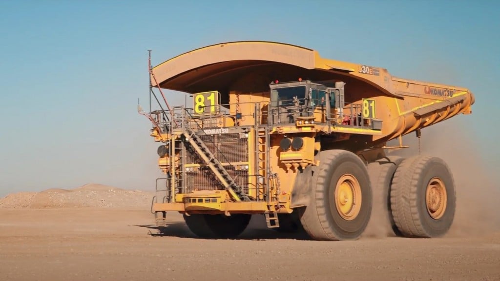 A large mining truck driving over a dirt surface.