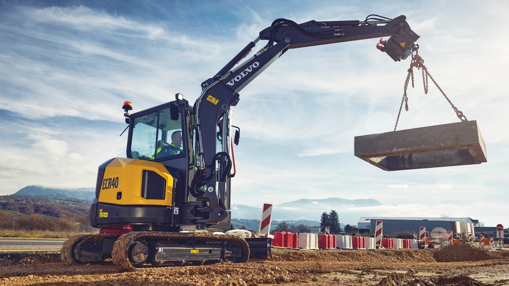 A mini excavator lifts a concrete structure