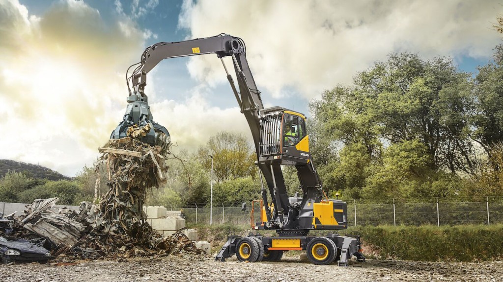 A material handler grapples scrap in a recycling yard.