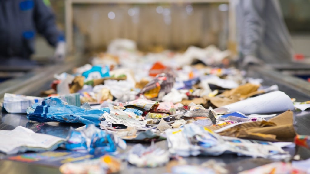 Paper moves down a conveyor in a recycling facility.