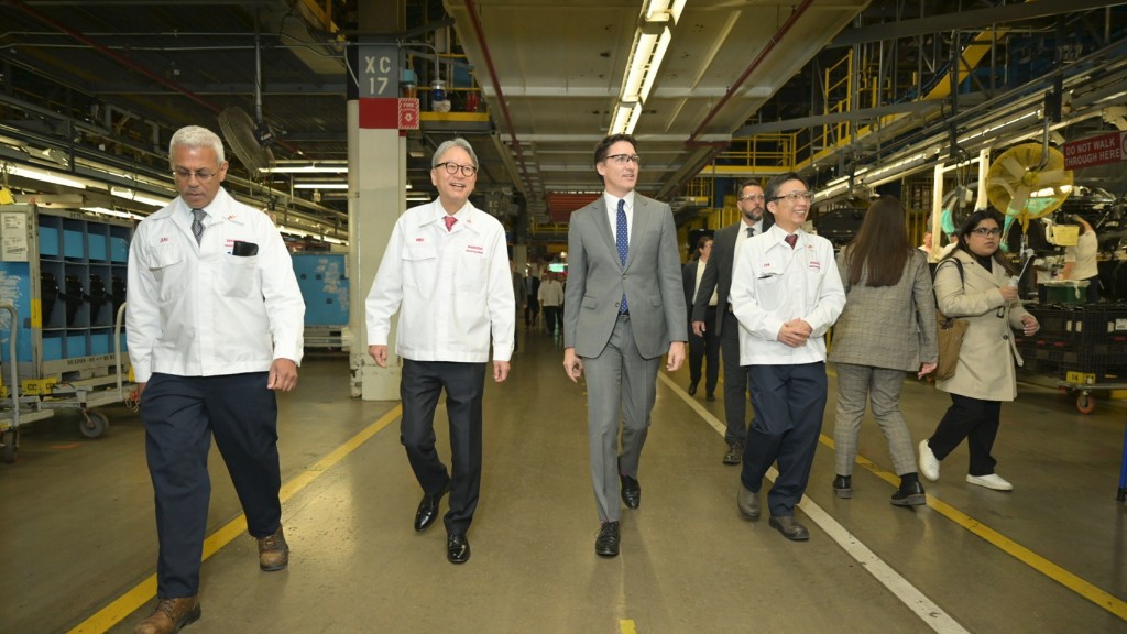 Justin Trudeau and multiple Honda employees walk down a hallway