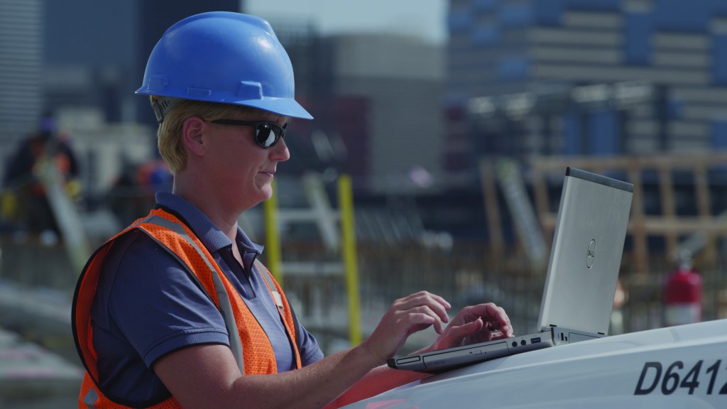 A worker uses a laptop on a job site