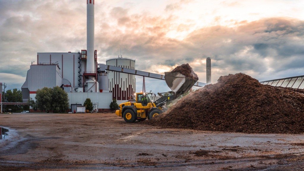 A wheel loader moves mulch toward a large pile