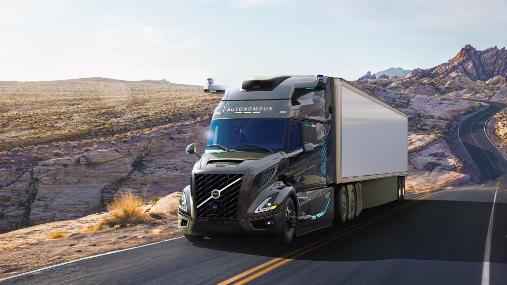 An autonomous truck driving through a desert landscape.