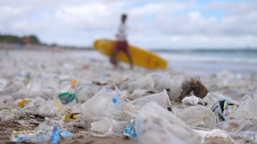 A surfer walks a beach full of plastic waste