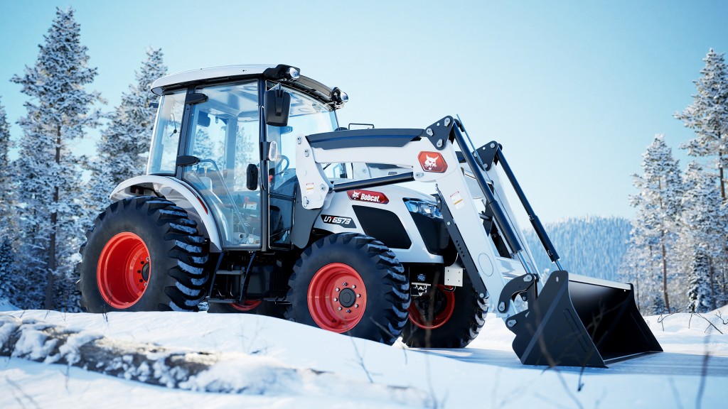 A utility tractor with loader bucket working in the snow.