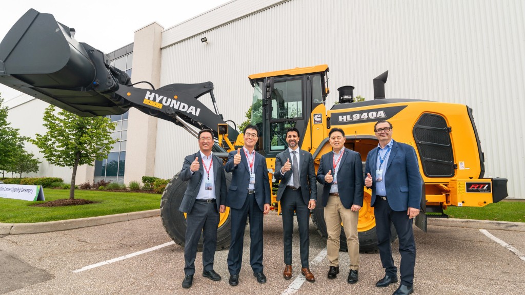 A group of people pose for a photo near a wheel loader