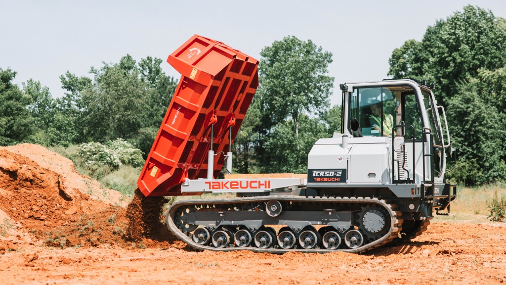 A crawler dumper dumps out a load of dirt on a job site