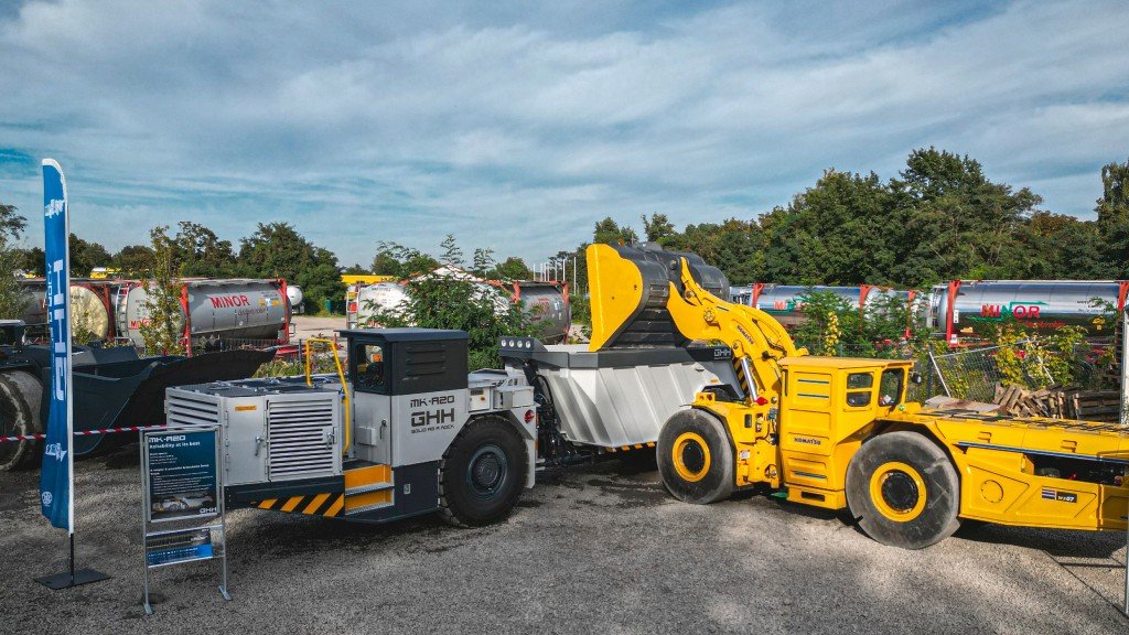 An underground loader dumps material into an articulated dump truck