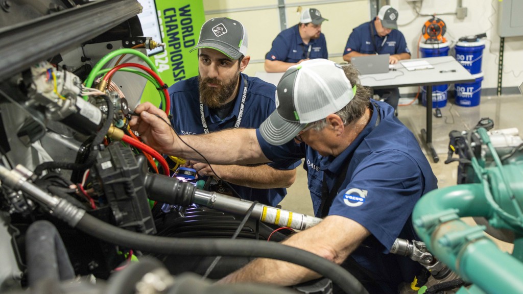 A service team checks over a truck engine