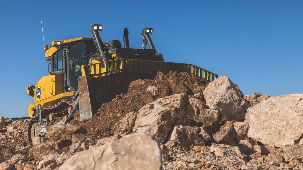 A John Deere dozer pushes earth and rocks on a job site