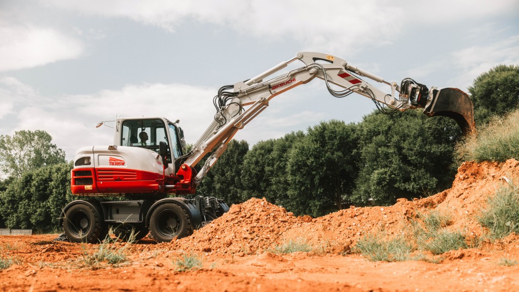 A wheeled excavator dumps dirt out of its bucket