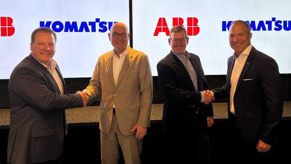 Men pose for a photo while shaking hands