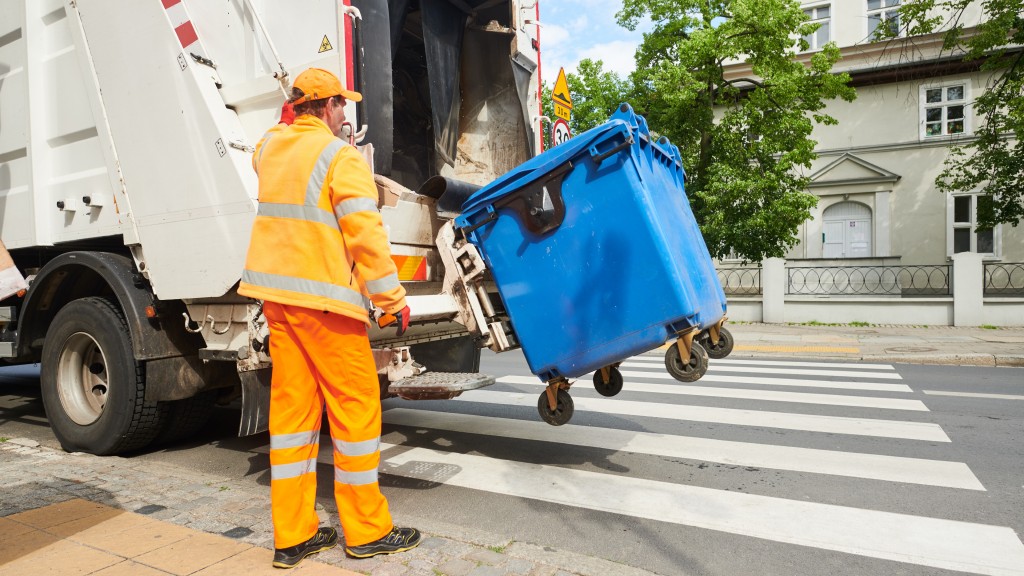 A collection truck operator uses a lift to dump a garbage bin's contents into a truck