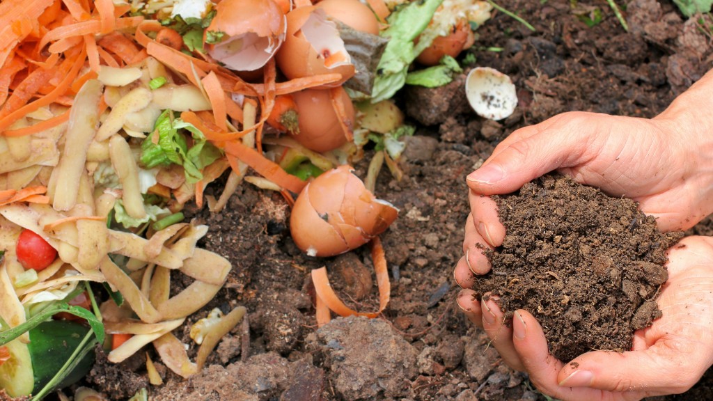 A hand holds a pile of soil near organics waste