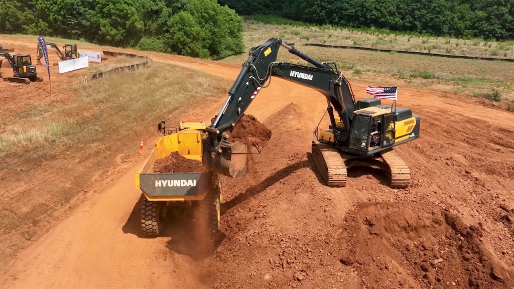 An excavator loads a truck during a competition