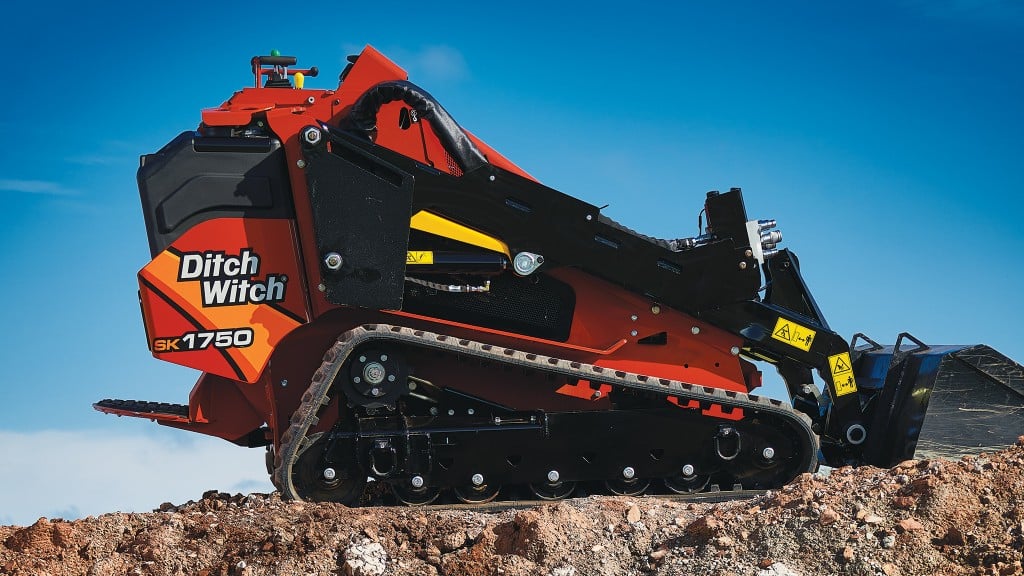 A mini track loader parked on a small outcropping