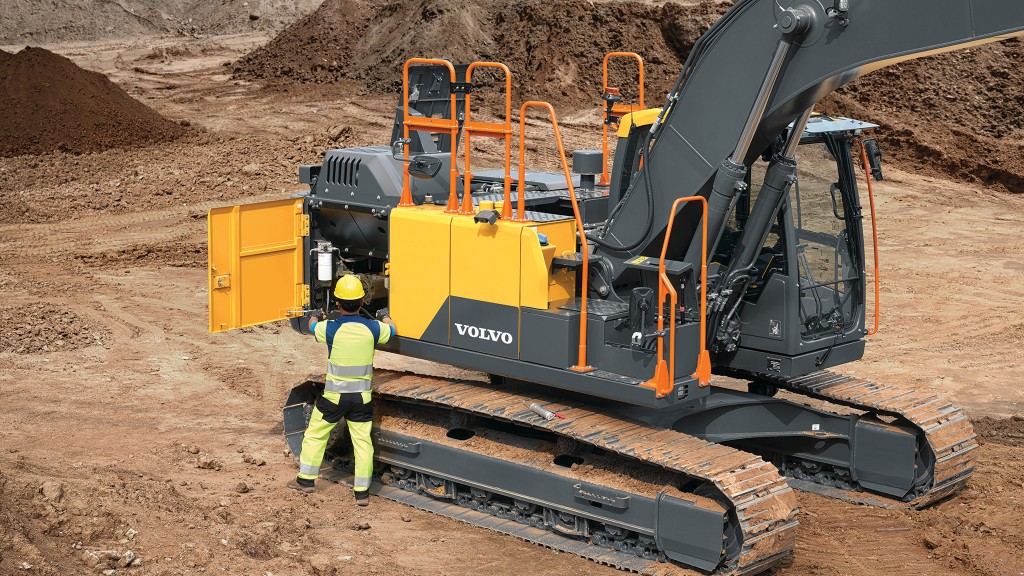 An operator inspects his excavator's engine compartment