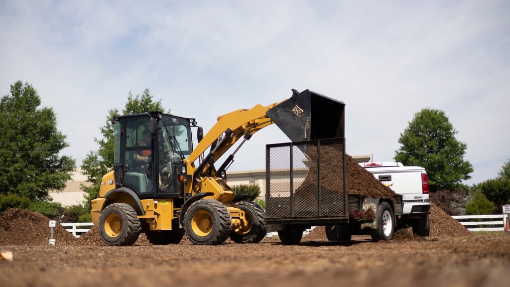 Caterpillar 903 compact wheel loader loading earth onto a tractor container