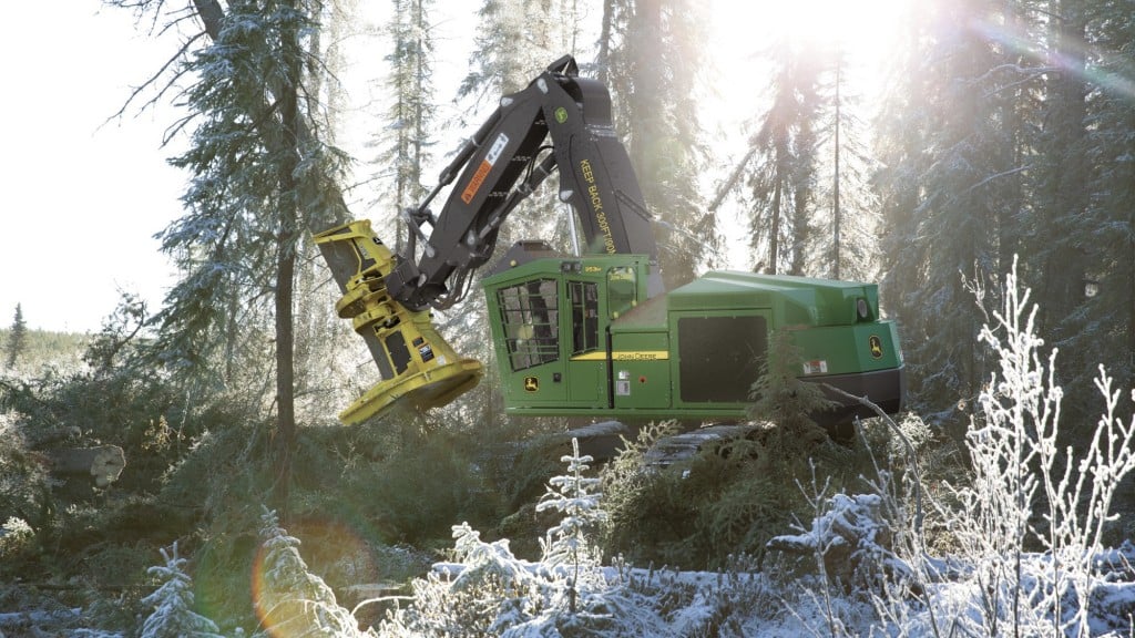 A John Deere feller buncher bunching trees in a snowy forest