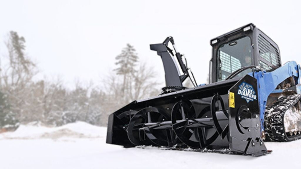 A large blue machine with a black snow blower attached to the front moving on a path filled with snow