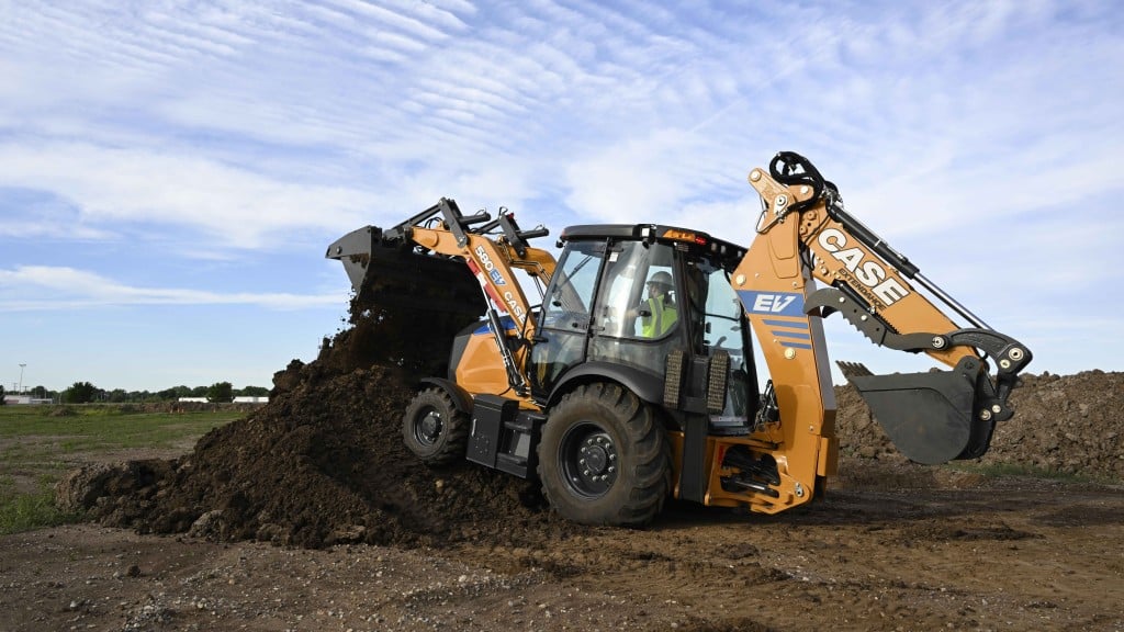 A yellow backhoe loader moving earth on a job site