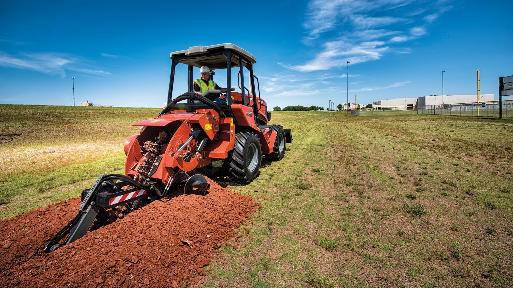 A ride-on trencher uses a trenching attachment in a field A ride-on trencher uses a trenching attachment in a field
